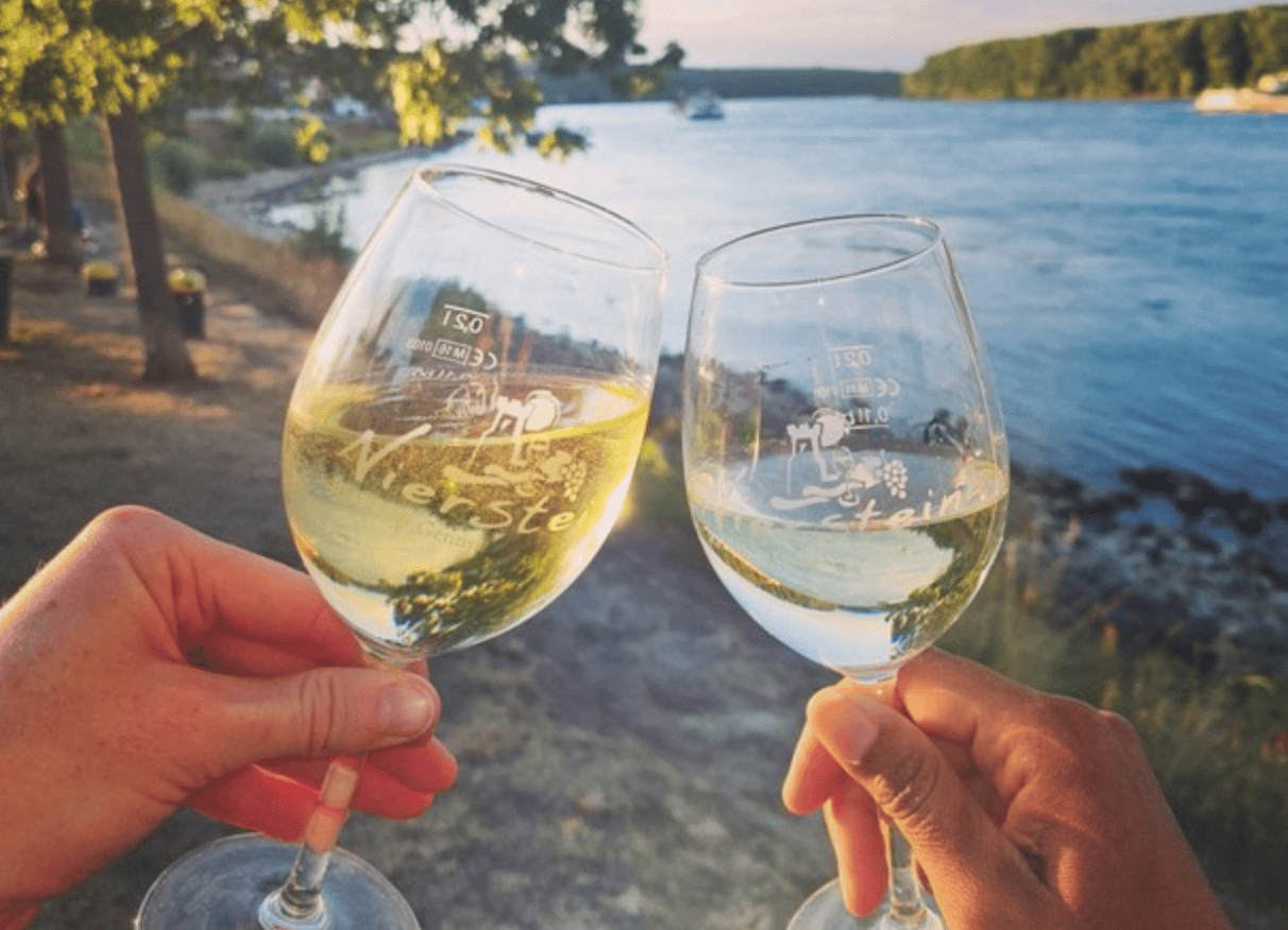 Zwei Gläser Niersteiner Wein stoßen vor dem Rhein an