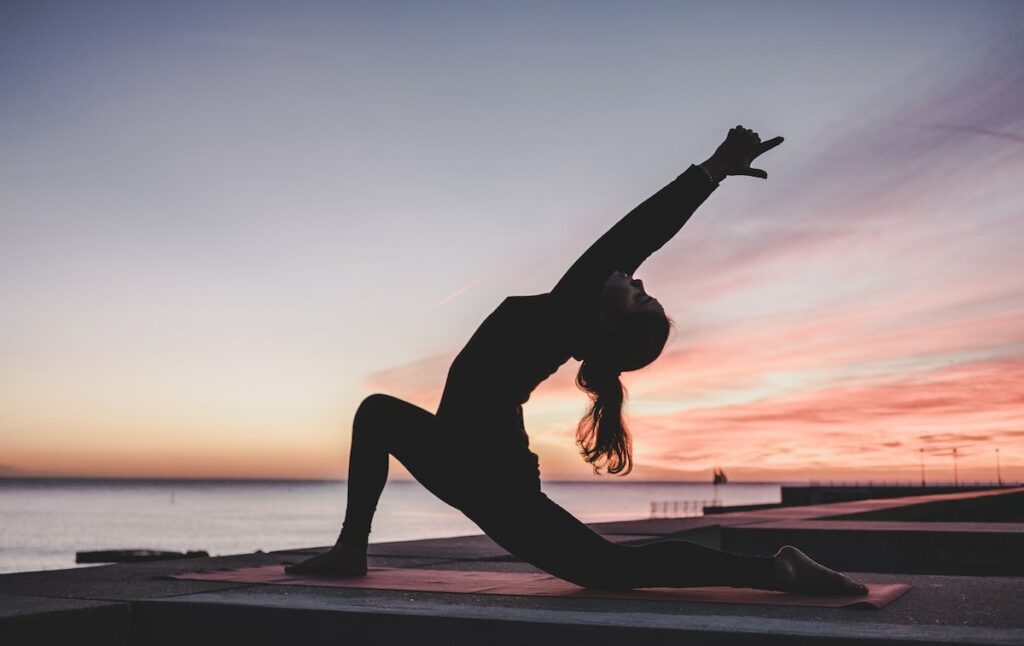 Eine Frau macht Yoga vor dem Sonnenuntergang