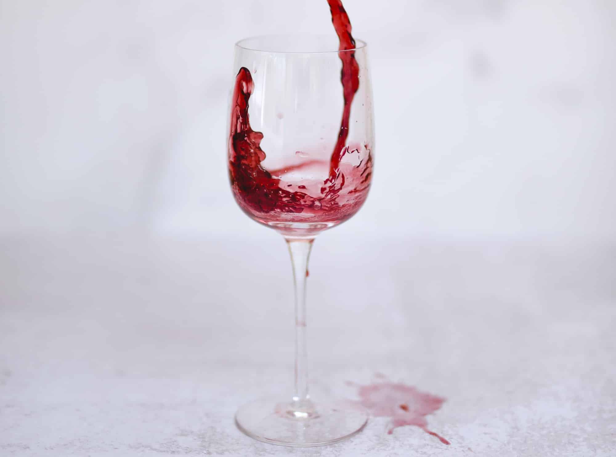 Ein Weinglas mit Rotwein, der verschüttet wurde