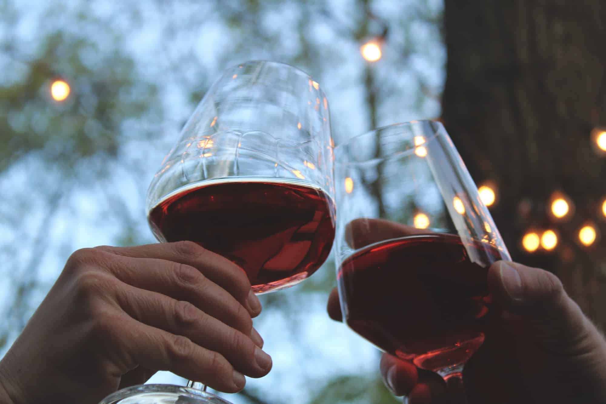 Zwei Weingläser mit Rotwein stoßen an