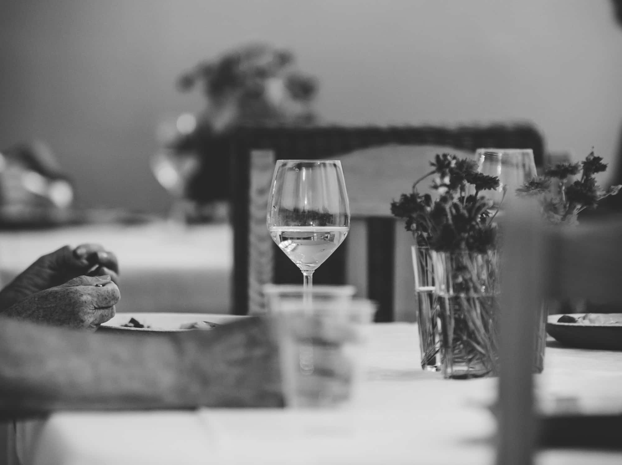 Ein Tisch mit einem Glas Sommerwein und Blumen in einer Vase