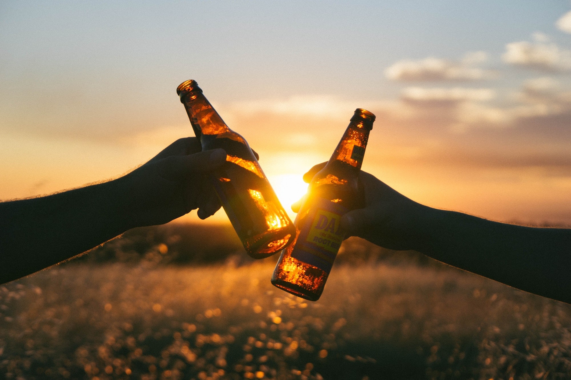 Personen stoßen beim Sonnenuntergang mit Bier an