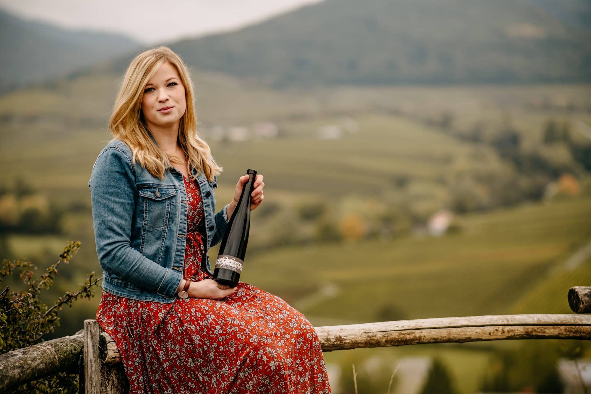 Jungwinzerin des Jahres: Vera Keller vom Weingut Keller mit einer Flasche Wein vor den Weinbergen